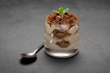 portion of Classic tiramisu dessert in a glass on concrete background