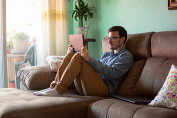 Fototapeta premium Young man with tablet on sofa at home