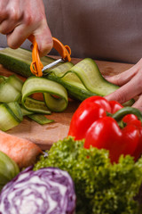 young woman in a gray apron cuts a cucumber