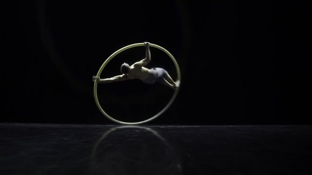 Muscular circus artist in the Cyr Wheel doing difficult tricks slow motion