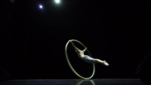 Circus performer artist in a Cyr Wheel in theatre on a black background