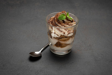 portion of Classic tiramisu dessert in a glass on concrete background