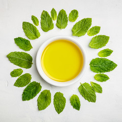 Olive oil and mint leaves on white stone background