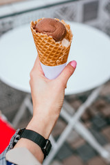 Chocolate and strawberry ice cream in waffle cups in hands of two girls best friends.