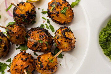 Tandoori aloo are roasted potatoes with Indian spices. It's a party appetiser served with green chutney. selective focus