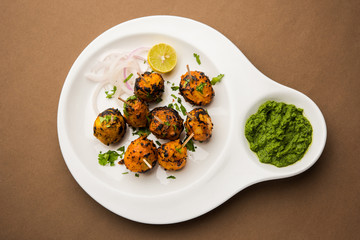 Tandoori aloo are roasted potatoes with Indian spices. It's a party appetiser served with green chutney. selective focus