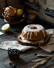 Homemade delicious bundt cake (with hole) with white glaze on top on wooden stand