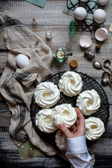 Overhead shot of homemade white mini meringue desserts pavlova on wicker metal stand on grey wooden table