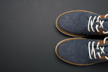 Flat lay composition of cropped stylish casual blue jean shoes on black color background. Male fashion concept, top view.