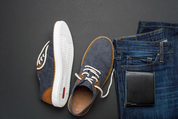 Mens summer casual clothes flat lay. Jeans, shoes and wallet. Mens summer casual clothing outfits and accessories flat lay on dark background, top view, fashion concept, copy space for text