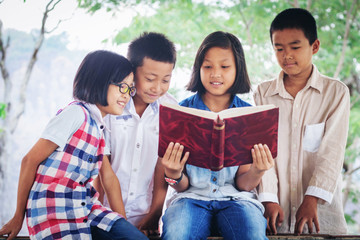Portrait of cute kids reading book in natural environment together