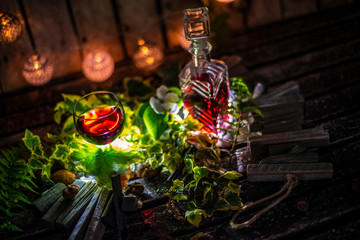 Red wine and green ivy on a wooden table in front of a wooden background with a creative lighting