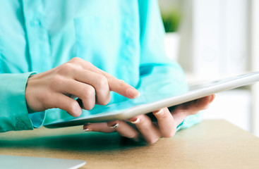 Close-up of female hands working with tablet computer. Woman using social network, texting and blogging.