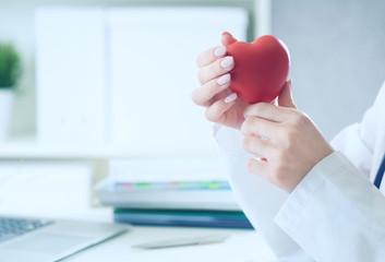 Female medicine doctor hold in hands red toy heart close -up.