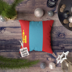 Happy New Year tag with Mongolia flag on pillow. Christmas decoration concept on wooden table with...