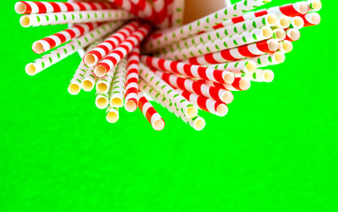 Red straws for juice in a paper cup on a green background