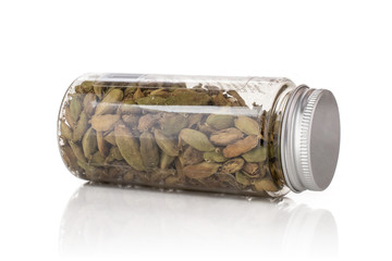 Lot of whole true cardamom pod lying on its side in a plastic bottle isolated on white background