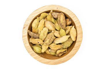 Lot of whole true cardamom pod in a wooden bowl flatlay isolated on white background