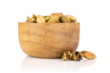 Lot of whole true cardamom pod near and in a wooden bowl isolated on white background
