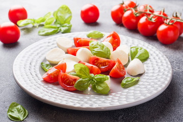 Caprese salad of tomatoes, mozzarella cheese and Basil on a dark background. Italian cuisine.