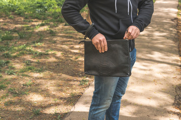 Man with snakeskin python handbag on nature background.