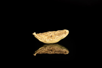 One whole true cardamom pod isolated on black glass