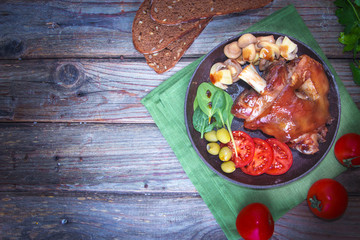 Delicious grilled pork knuckle with fresh vegetables and pickled mushrooms. Delicious food.