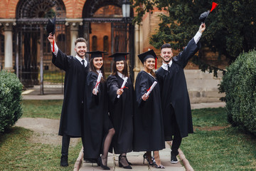 Portrait of multiracial graduates holding diploma and smiling!
