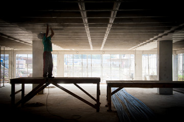 Silhueta de trabalhador da Construção Civil lixando o teto