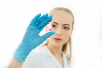 Hand of a lab technician holding a mini test tube with blood sample for analysis.