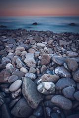 Rock seaside shore with black round stone on the island