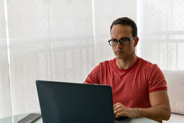 mature man in glasses working at home and messing on his computer (natural light)