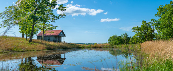 Rural old house barn reflected on pond water, panoramic view in northwest Arkansas, Ozark mountains, beautiful scenic view
