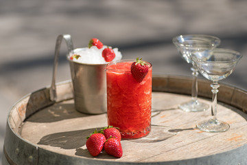 Summer Slushy made from strawberries, smoothies, ice with some ingredients nearby over wooden background
