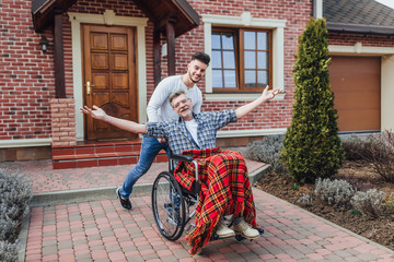 Senior father in wheelchair and young son on a walk near nursing home! - Powered by Adobe