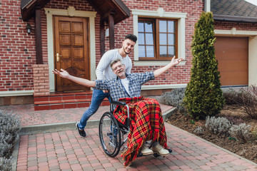 Senior father in wheelchair and young son on a walk near nursing home!