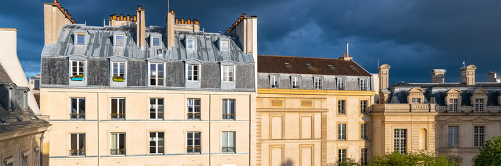 Fototapeta na wymiar Paris, beautiful building in the evening light, under a thunderstorm sky, in the Marais, typical parisian facades and windows 