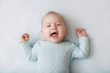 Portrait of a smiling baby in bed. Baby smiling and looking up to camera. Good morning!
