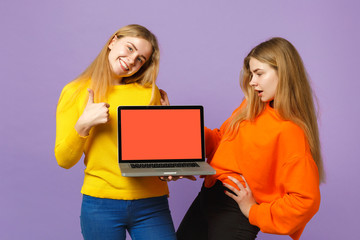 Two young blonde twins sisters girls showing thumb up holding laptop pc computer with blank empty...