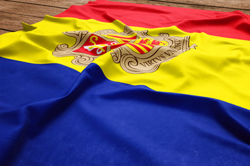 Flag of Andorra on a wooden desk background. Silk Andorran flag top view.