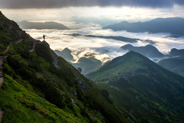 Wide mountain panorama. Small silhouette of tourist with backpack on rocky mountain slope with...