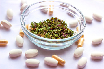 Dried herbs in a bowl on nutritional supplements pills background. Alternative herbal medicine, naturopathy and homeopathy, medical pharmaceutical drugs, organic vitamins and multivitamins concept