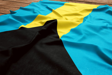 Flag of Bahamas on a wooden desk background. Silk Bahamian flag top view.