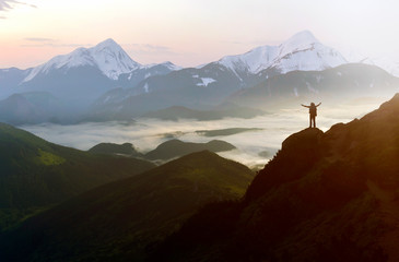 Wide mountain panorama. Small silhouette of tourist with backpack on rocky mountain slope with...