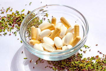 Nutritional supplements pills in a bowl on dried herbs background. Alternative herbal medicine, naturopathy and homeopathy, medical pharmaceutical drugs, organic vitamins and multivitamins concept