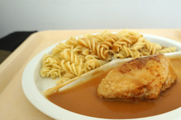 Chicken breast served with noodles and gravy on a tray