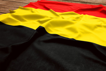 Flag of Belgium on a wooden desk background. Silk Belgian flag top view.