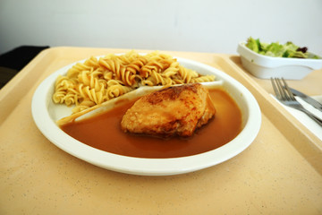Chicken breast served with noodles and gravy on a tray