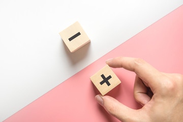 Pros and cons concept, Hand choose wood blog with plus and minus on white and pink background, flat...
