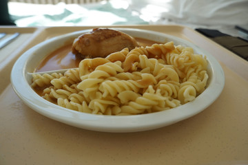Chicken breast served with noodles and gravy on a tray